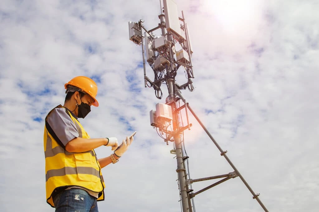Power Source Monitoring for Telecom Towers with a technician inspecting cellular tower equipment.